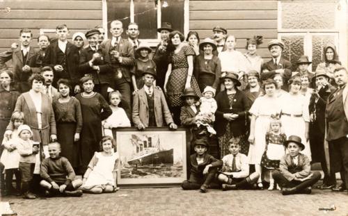 Un groupe d’émigrants pose autour de la photo d’un paquebot de la Cunard Line, à Rotterdam, 1900.